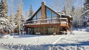A lodge with a stone chimney, wooden deck, and snow-covered surroundings. - Group Ski Getaway Near the Base of Chairlift 8! (Brian Head)