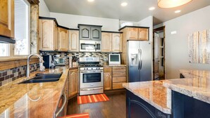 A modern kitchen with wooden cabinets, stainless steel appliances, and a granite countertop. - Group Ski Getaway Near the Base of Chairlift 8! (Brian Head)