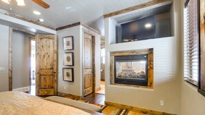 A bedroom with a large bed, wooden doors, a fireplace, and a ceiling fan. - Group Ski Getaway Near the Base of Chairlift 8! (Brian Head)