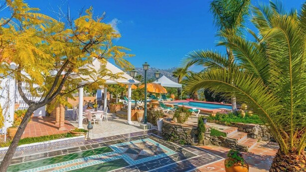 Ein Poolbereich mit Liegestühlen, einer Pergola und einem weißen Zelt.