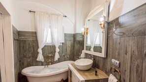 Bathroom features a bathtub, round sink, and mirror.