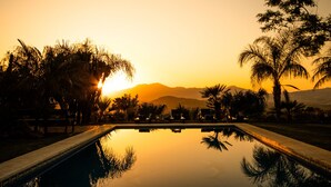 A pool with lounge chairs and palm trees at sunset. - Cubo's Finca Los Dragos. Pool, wifi and AC/heating (Alhaurín el Grande)