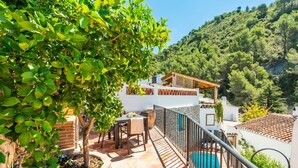 A terrace with a table and chairs, a pool, and a view of a hillside. - Casa Alhama Frigiliana by Ruralidays (Málaga)