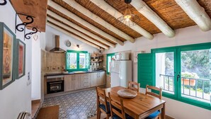 A rustic kitchen with wooden beams, a tiled floor, and a dining area with a table and chairs. - Casa Alhama Frigiliana by Ruralidays (Málaga)