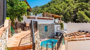 A villa with a stone pool, outdoor seating, and a view of the surrounding forest. - Casa Alhama Frigiliana by Ruralidays (Málaga)
