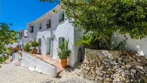 A white building with a stone wall and potted plants. - Casa Alhama Frigiliana by Ruralidays (Málaga)