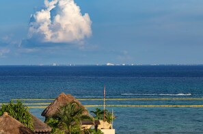A coastal view with a clear sky, a large cloud formation, and a distant city skyline. - Singular Joy Vacation Rentals (Playa del Carmen)
