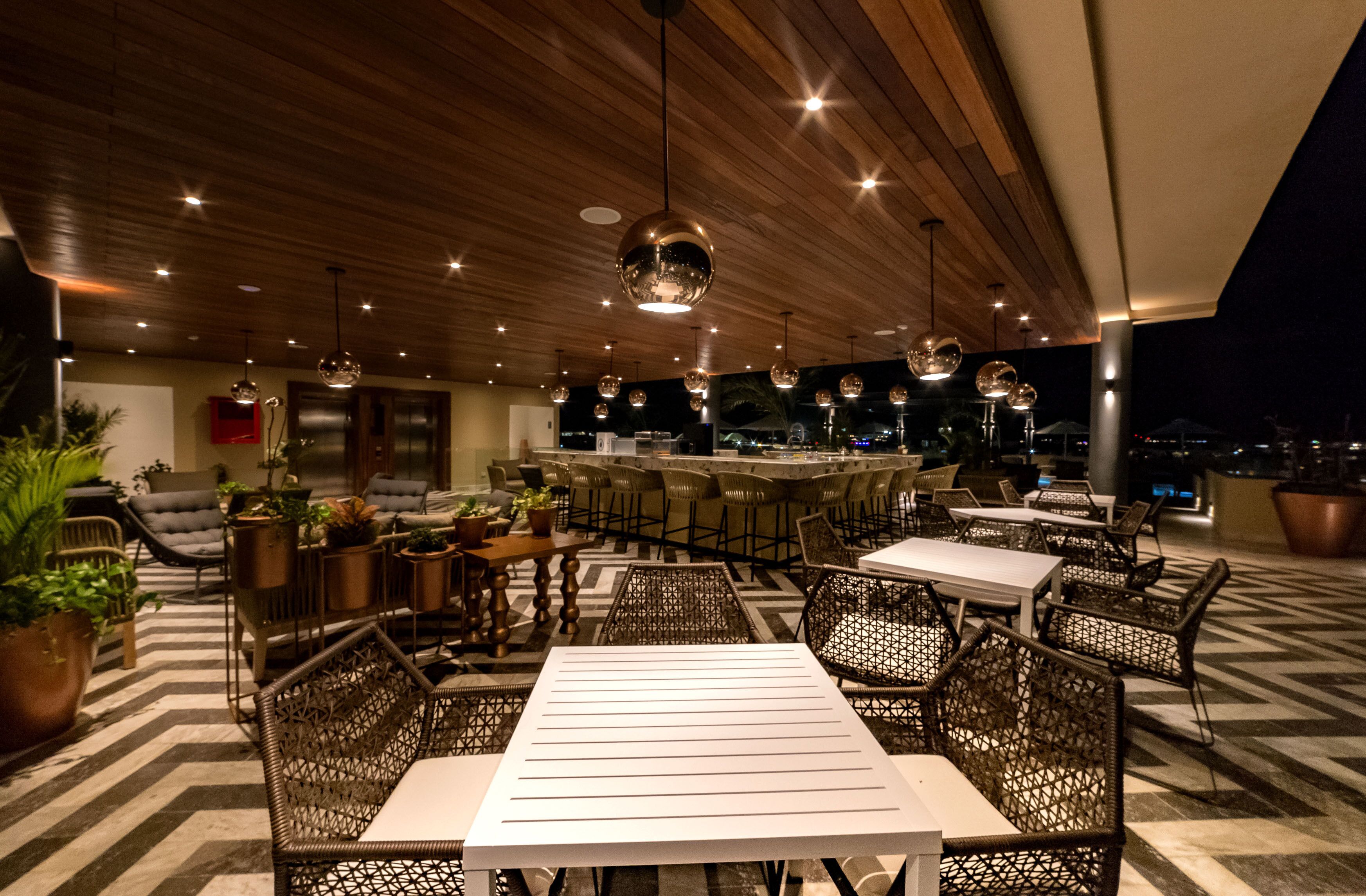 Un espace de restauration en plein air doté d’un plafond en bois, de luminaires sphériques suspendus et d’un comptoir de bar.