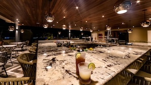 A bar area with a marble countertop, wicker chairs, and hanging pendant lights. - Singular Joy Vacation Rentals (Playa del Carmen)
