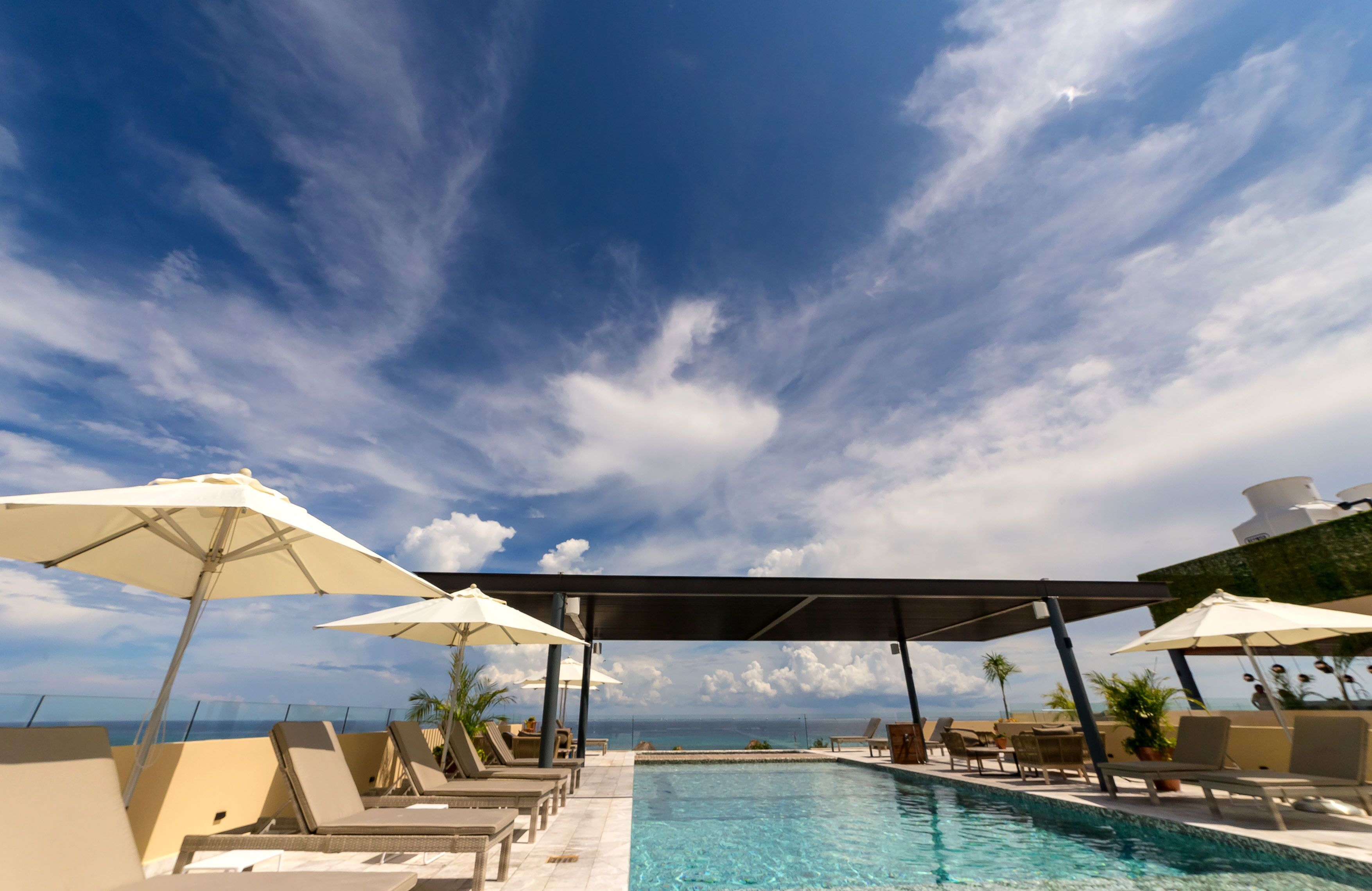 A pool area with lounge chairs and umbrellas, overlooking a body of water.