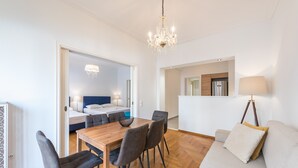 Una sala de estar moderna con una mesa de comedor de madera, sofás grises y una lámpara de araña.