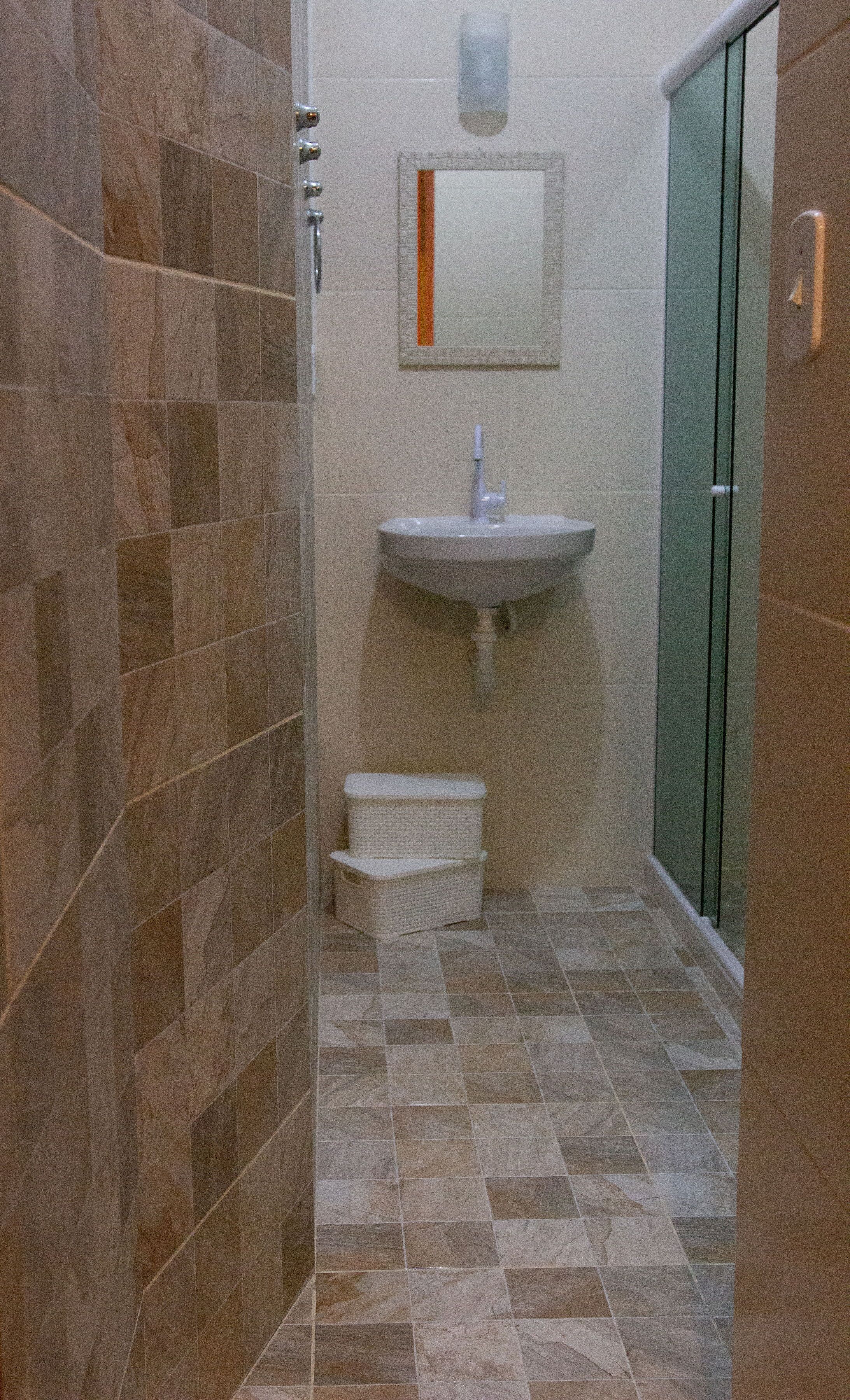 A bathroom with a shower, sink, and a small basket.