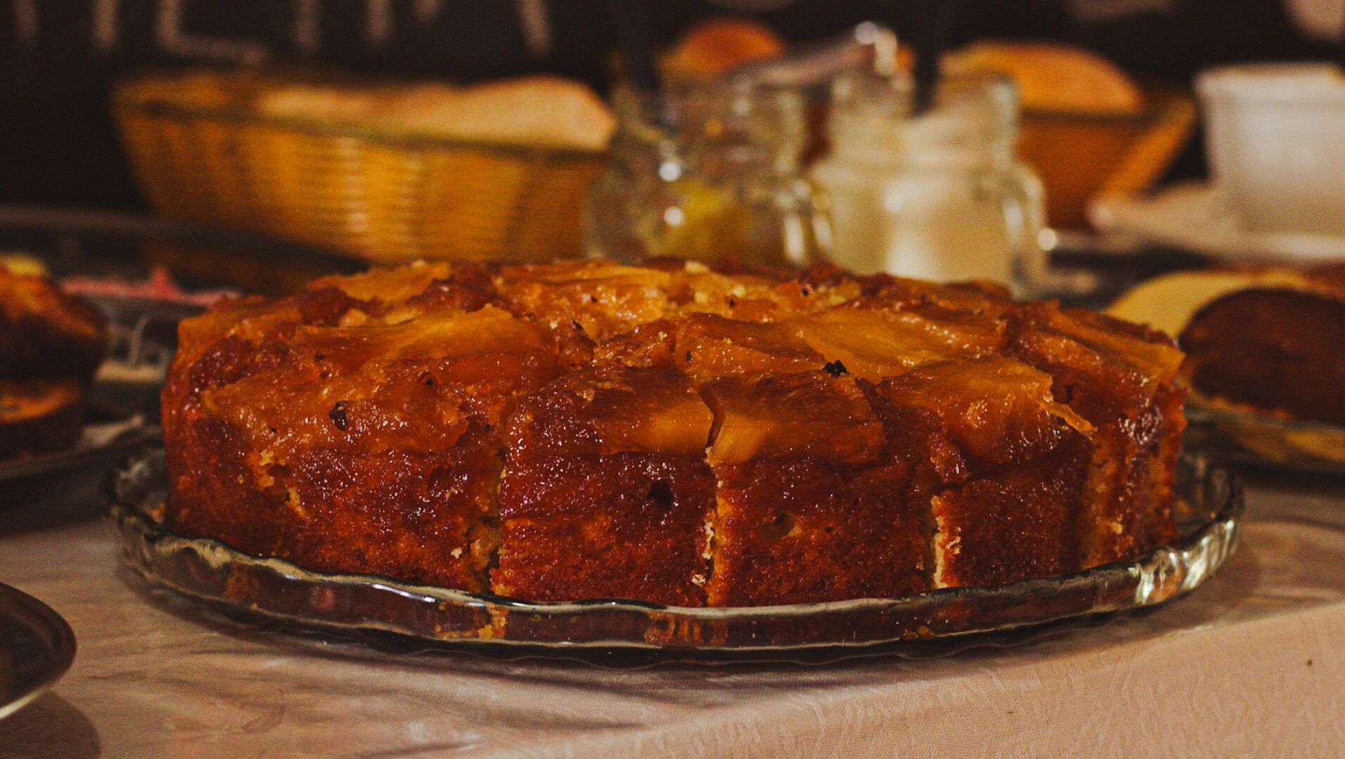 Un pastel redondo con una cobertura caramelizada, sobre un plato de cristal.