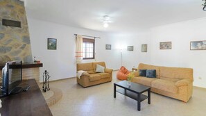 Ein Wohnzimmer mit zwei Sofas, einem Couchtisch, einem Fernseher und einer Steinwand.