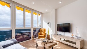 A modern living room with a large window, a sofa, a coffee table, and a TV.