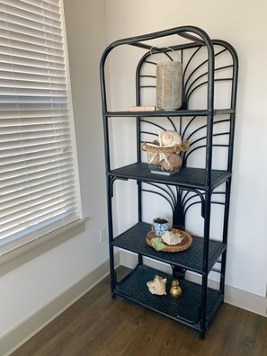 A stylish shelf unit near a window, featuring decorative items and a potted plant.