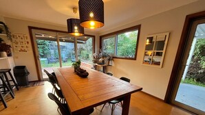 A dining area with a wooden table, black chairs, and pendant lights.