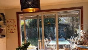A dining area with a wooden table, black chairs, and a hanging light fixture.