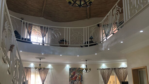 Un amplio salón con un conjunto de sofás, una mesa de comedor y una escalera que conduce a un nivel superior.