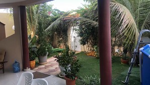 Un patio cubierto con suelo de baldosas, plantas en macetas y un dispensador de agua.