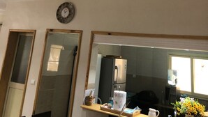 Una habitación de hotel con un espejo grande, un reloj, una estantería de madera con artículos de aseo y paneles decorativos en la pared.