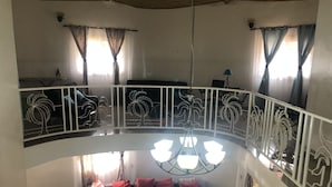 Amplia sala de estar con balcón curvo, un conjunto de sofás y una araña.