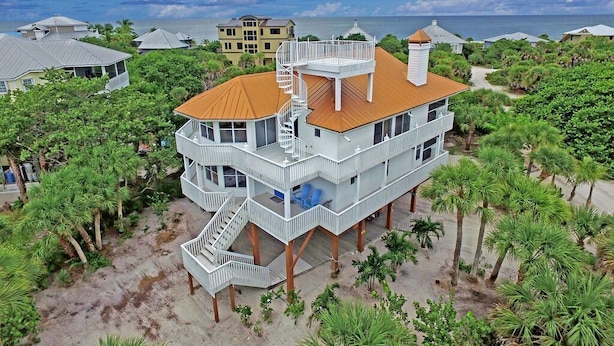 Une maison à plusieurs étages située en bord de mer, dotée d’une tour centrale, de nombreux balcons et d’un escalier en colimaçon.