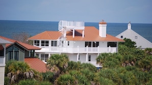 Une maison située sur la côte, avec une façade blanche, un toit rouge et un balcon donnant sur la mer.