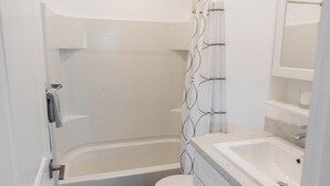 Moderni kylpyhuone, jossa on kylpyamme, wc ja pesuallas.