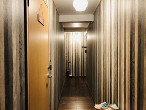 A narrow hallway with striped walls and a wooden door on the left. - GuestHouse Amamin - Hostel (Amami)