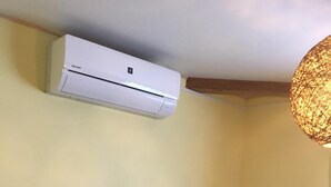 Quarto com cama, ar-condicionado fixado no teto e luminária com textura.