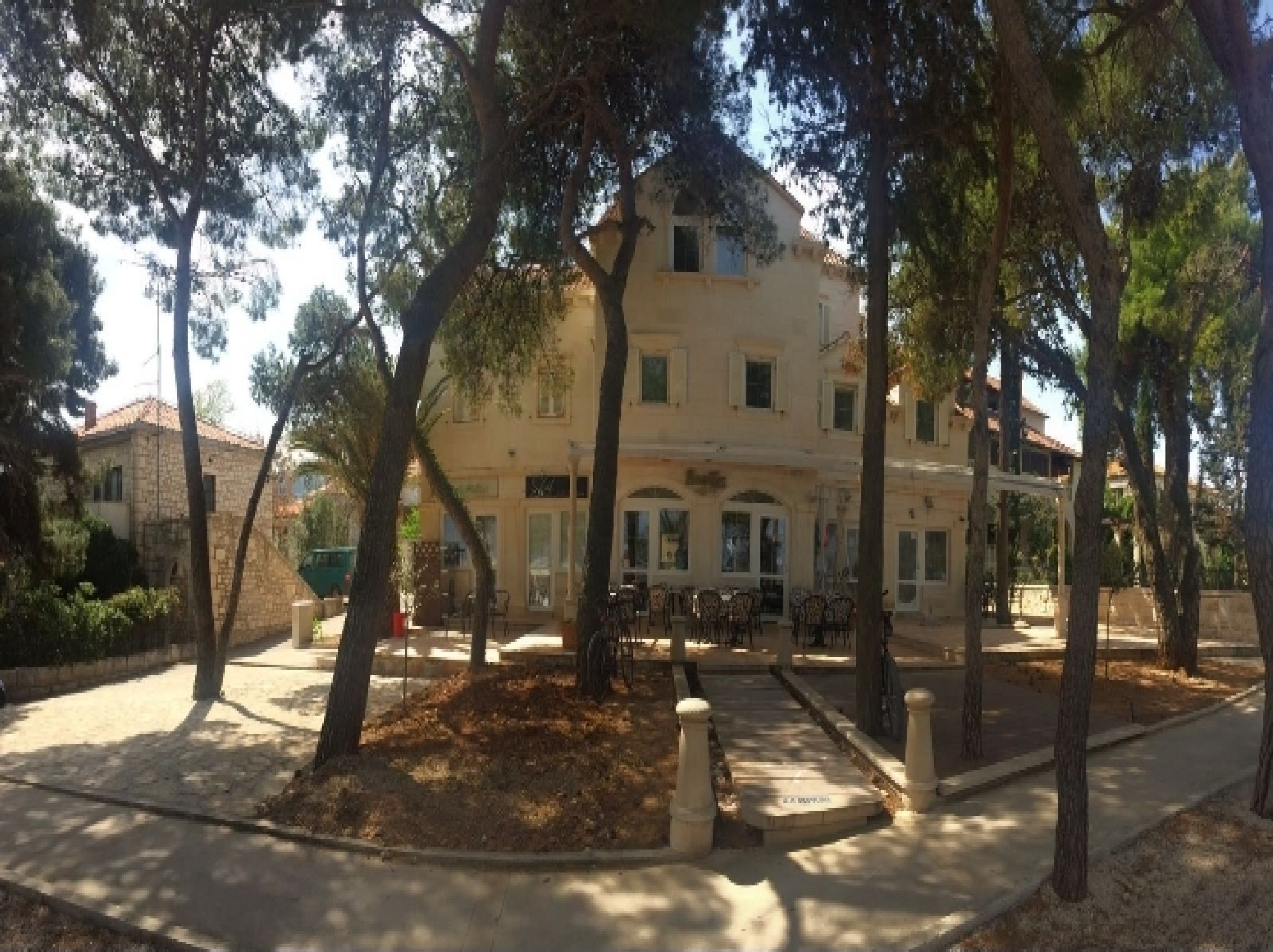 Ein Gebäude mit einem zentralen Innenhof, der von Bäumen umgeben ist, mit einem gepflasterten Weg und einer Außen-Sitzgelegenheit.