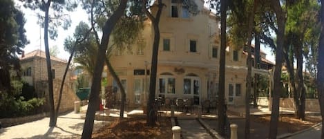 Un edificio con un patio central rodeado de árboles, que cuenta con un camino pavimentado y un espacio para sentarse al aire libre.
