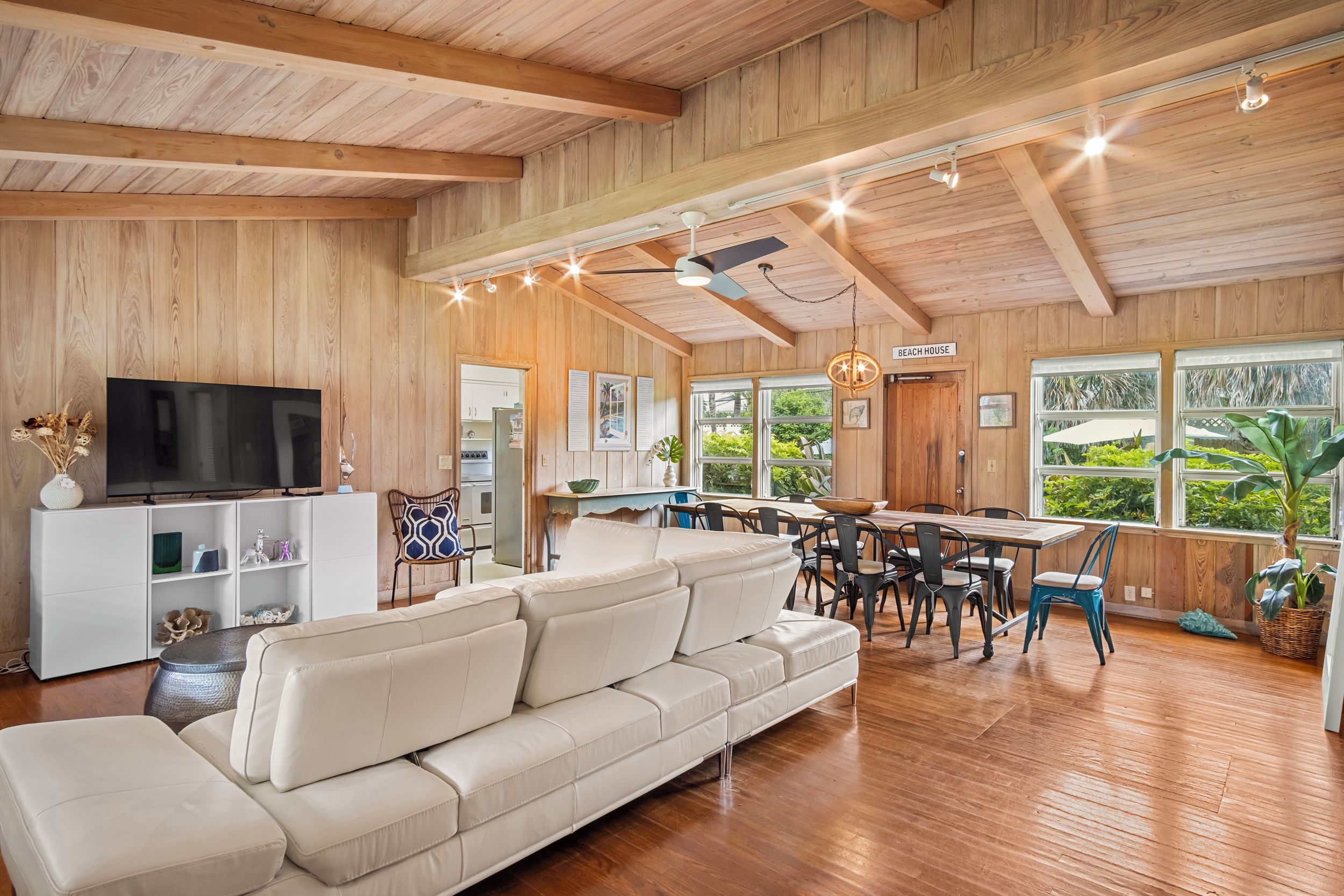 A spacious living room with a large sofa, a television, and a dining area with a table and chairs.