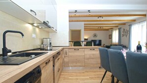 Una cocina moderna con encimera de madera, lavavajillas integrado y grifo negro.