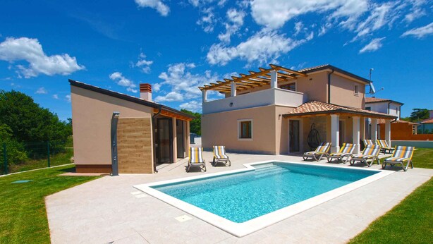 Una casa de dos pisos con piscina y zona de estar al aire libre.
