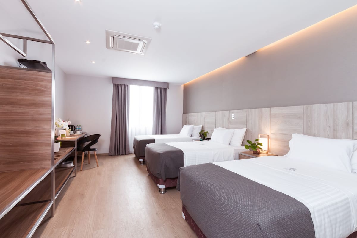 A hotel room with two beds, a desk, a chair, and a wardrobe.