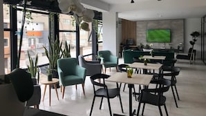 A modern interior with a dining area, sofas, and a TV mounted on the wall. - Surya Lima (Lima)
