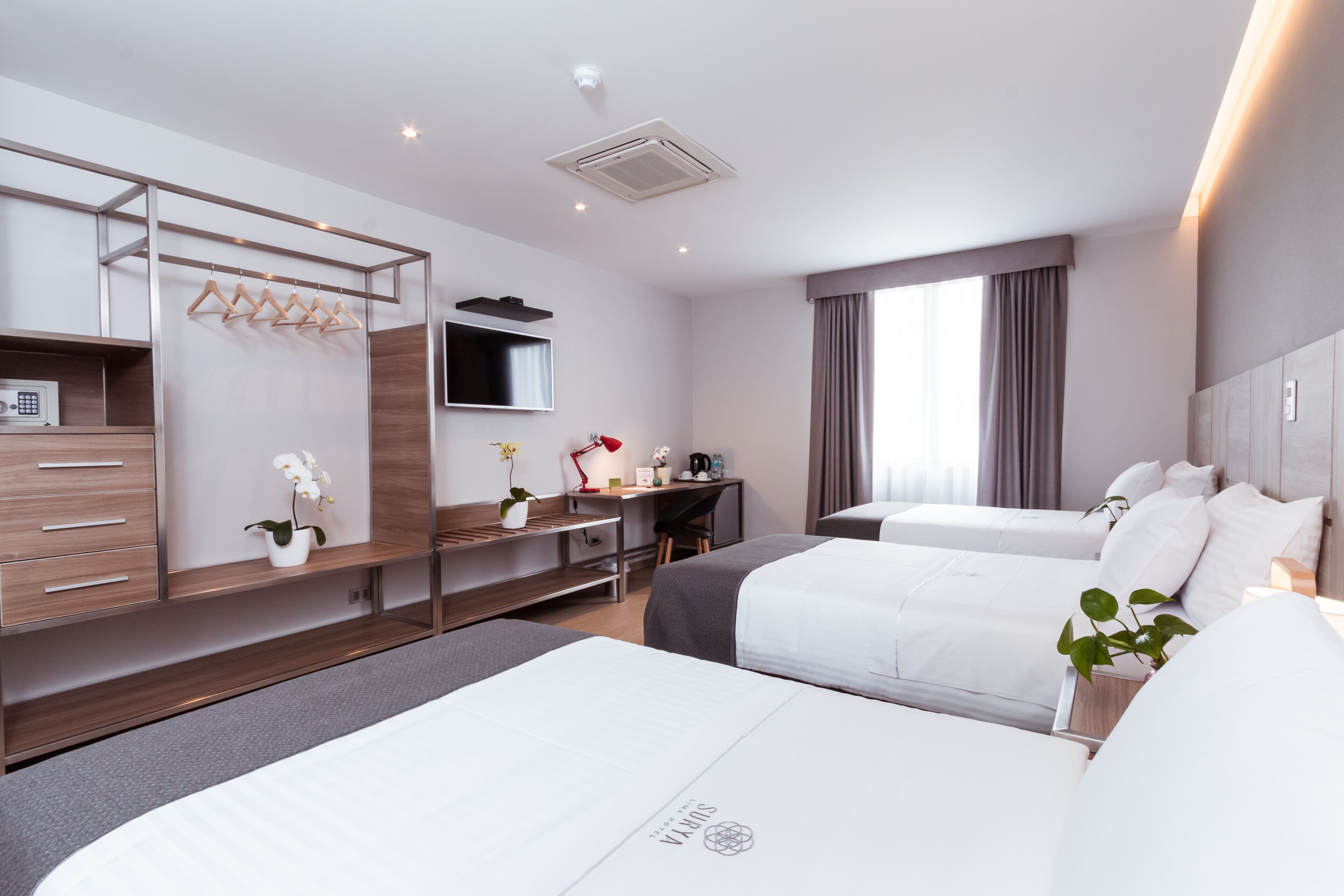 Ein modernes Hotelzimmer mit zwei Betten, einem Schreibtisch, einem Fernseher und einem Kleiderschrank.