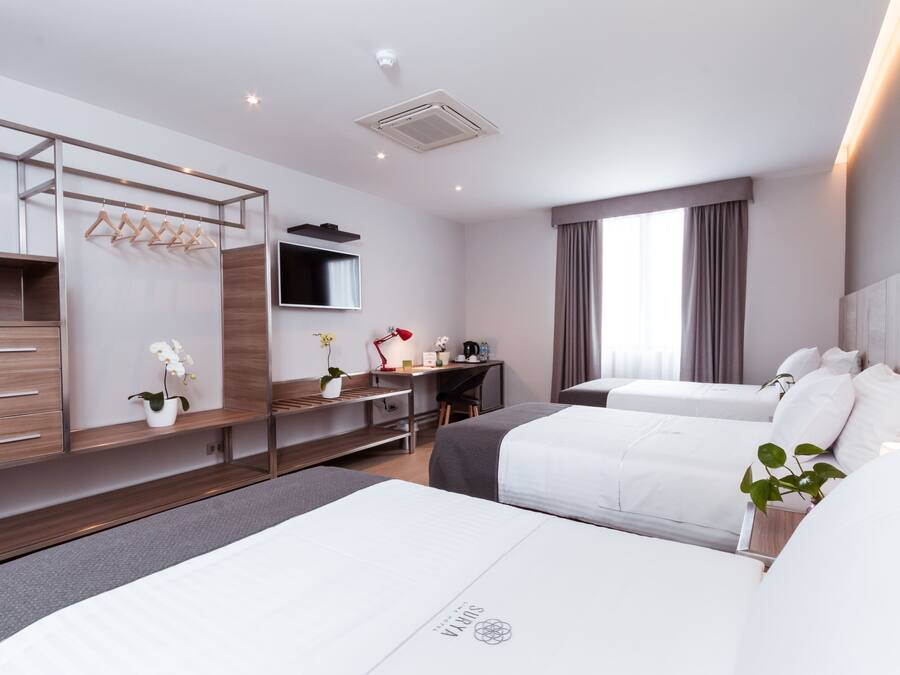 Una habitación de hotel moderna con dos camas, un escritorio, un televisor y un armario.