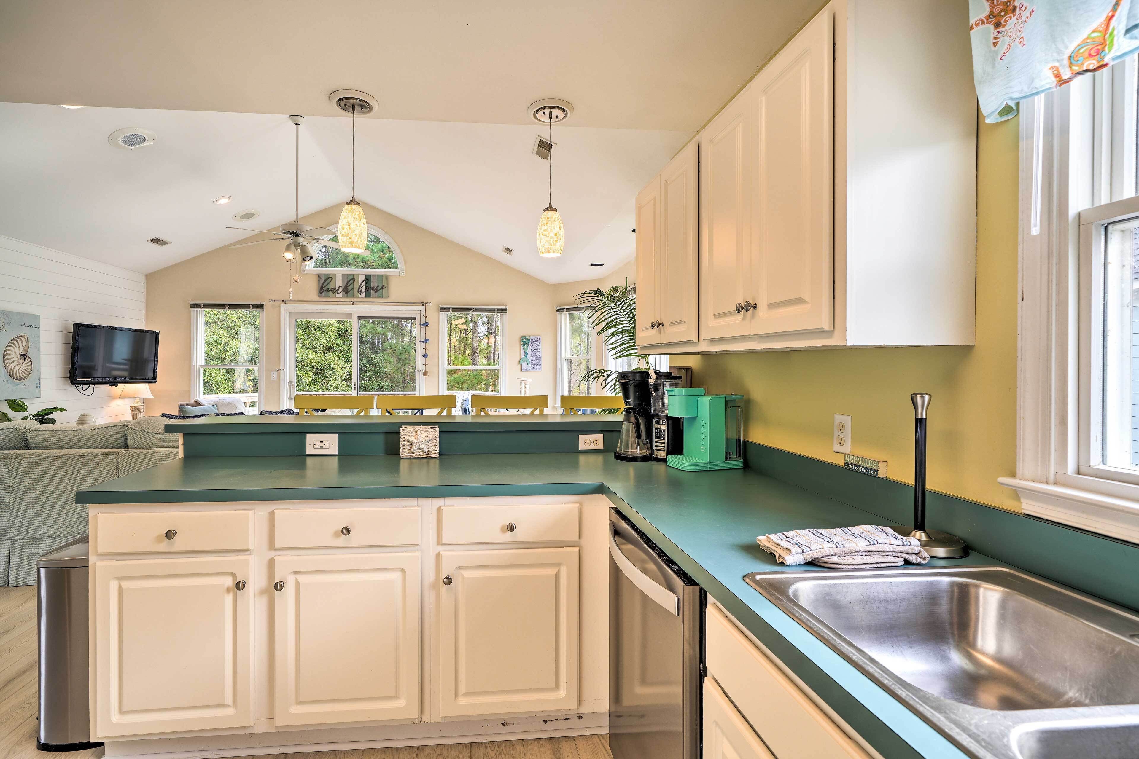 A kitchen with white cabinets, a green countertop, and a stainless steel sink.