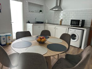 A modern kitchen with white tiled backsplash, a built-in microwave, and a washing machine.