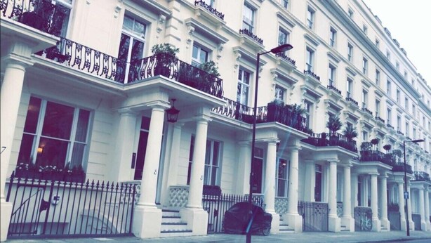 A row of white buildings with balconies, columns, and a street lamp. - Luks Apartments (London)