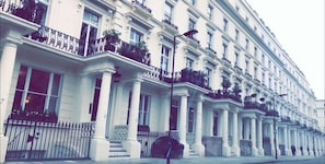 A row of white buildings with balconies, columns, and a street lamp. - Luks Apartments (London)