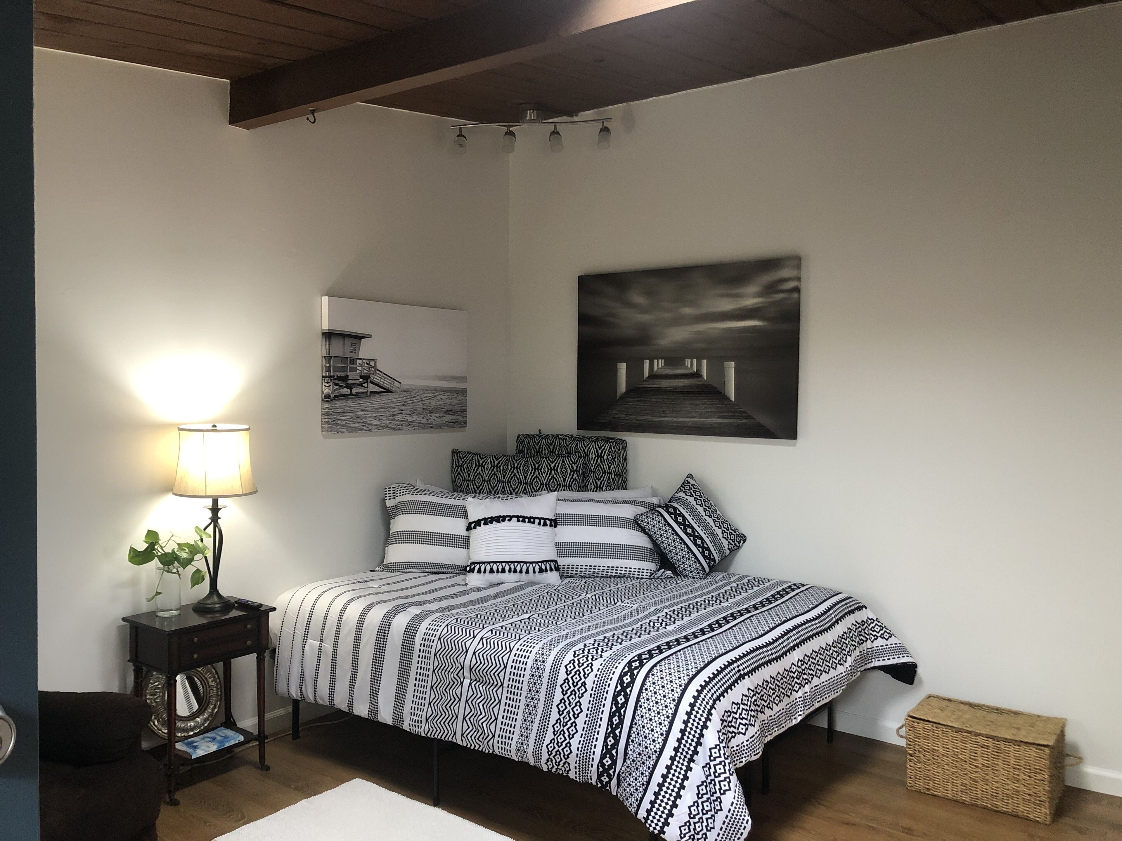 Une chambre à coucher comprenant un lit, une table de chevet avec une lampe et deux œuvres d’art accrochées au mur.
