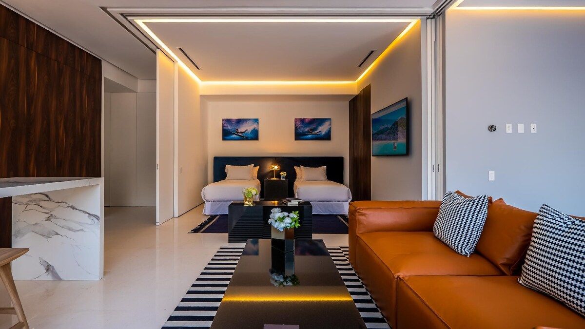 Una habitació d'hotel moderna amb un llit, un sofà, una taula de cafè i obra d'art a les parets.