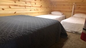 A small, cozy room with two single beds, a wooden ceiling, and a carpeted floor. - Frenchy's Hideaways Cabin #6 (Custer)