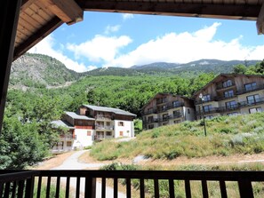 Un complejo turístico de montaña con edificios de madera, balcones y una vista despejada de las colinas circundantes.