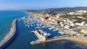 Vue aérienne d’une ville côtière avec un port de plaisance, des bâtiments et une plage.