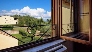 Un balcon doté d’une balustrade en fer forgé, donnant sur un quartier résidentiel avec des maisons et des arbres.